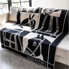 a black and white horse blanket sitting on top of a couch next to a window