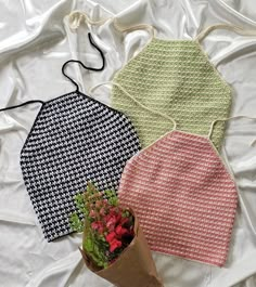 three aprons on a bed with flowers in the middle one has a brown paper bag