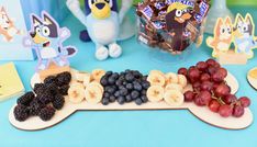 an assortment of fruit and snacks displayed on a blue table with penguin figurines