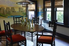 a dining room table with four chairs and a painting on the wall in the background