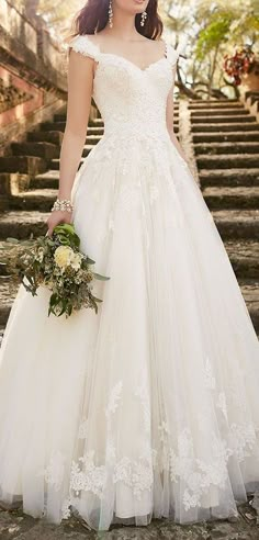 a woman in a wedding dress is standing on some stone steps and holding a bouquet