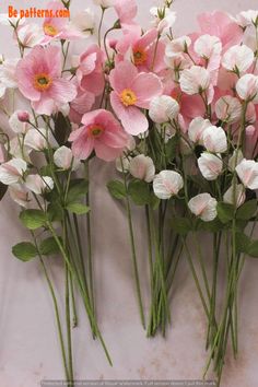 pink and white flowers sitting on top of a marble counter next to each other in front of a wall