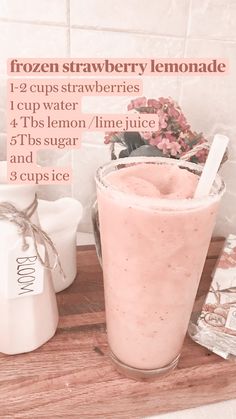 a smoothie in a glass next to a jug of frozen strawberry lemonade