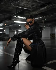 black and white photograph of woman in high heeled boots sitting on the ground with her legs crossed