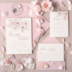 the wedding stationery is laid out on top of shells and seashells, along with pink flowers