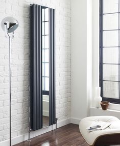 an empty room with a white brick wall and wooden flooring, along with a black radiator