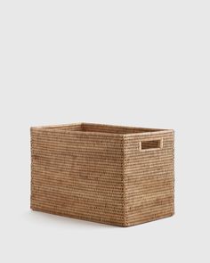 a large woven basket with handles on the bottom and sides, in front of a white background