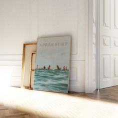 an empty room with two framed pictures and a surfboard on the floor next to it