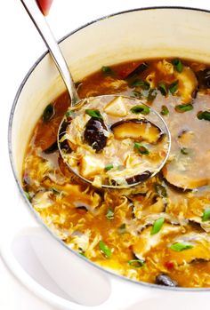 a ladle full of soup being stirred by a spoon