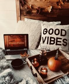 a tray with candles, pumpkins and an open laptop on it sitting on a bed