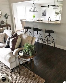 a living room filled with furniture next to a counter top and bar stools in front of a window