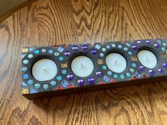 three candles are sitting in a decorative box on a wooden table with wood grain flooring