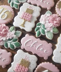 decorated cookies with pink and white frosting are arranged on a wooden table in the shape of flowers