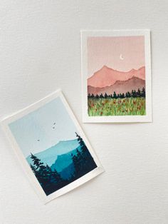 two cards with mountains in the background and a bird flying over them on a white surface