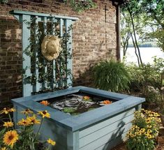 an outdoor fire pit with sunflowers and other flowers in the foreground, next to a brick building