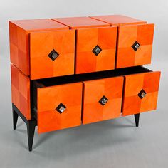 an orange chest of drawers with black diamond knobs on each drawer and two legs