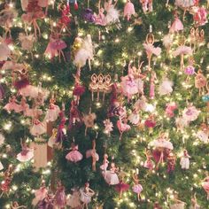 a christmas tree decorated with many different types of dolls and ornaments, all hanging from it's sides