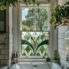 a bath tub sitting under a window next to a green leafy design on the wall