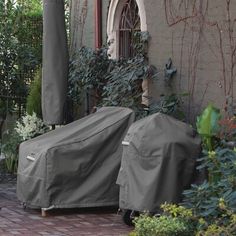 there are two bbq grill covers on the back of this house, and one is covered by a gray cover