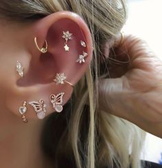 a woman wearing three different ear piercings on her left ear and the other one is gold