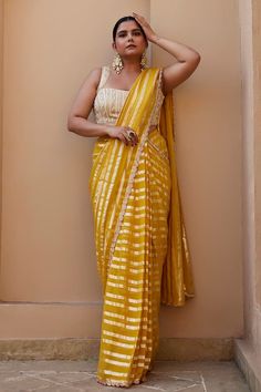 Yellow georgette saree with delicate embroidered border. Paired with a contrast ivory glass bead and pearl work embroidered padded blouse. - Aza Fashions