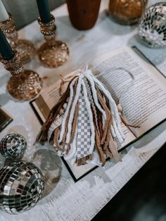 an open book sitting on top of a table next to some glass vases and candles