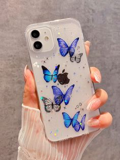 a woman holding up a phone case with blue butterflies on it and glitter in the back