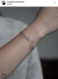 a woman's arm with a small flower tattoo on it