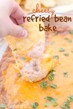 a hand dipping a tortilla chip into a bowl of cheesy refried bean bake