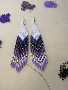 purple and white seed bead earrings with black beads on the floor next to it