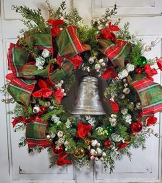 a christmas wreath with red and green bows, bells and greenery on the front door