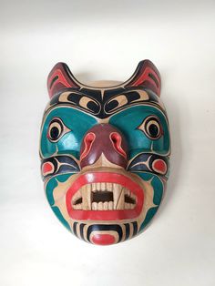 a wooden mask on a white surface with an animal's face in the center