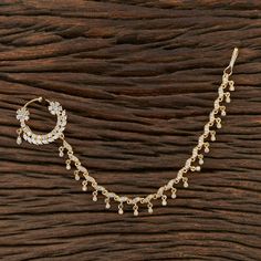 a gold necklace and earring on top of a wooden table