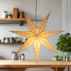 a star shaped light hanging from the ceiling in front of a wooden table and shelves