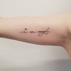 a woman's arm with the words i am enough written in cursive writing