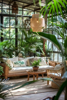 a living room filled with lots of plants and wicker furniture in front of large windows