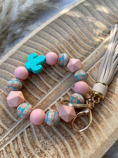 a pink and blue beaded bracelet with an elephant charm is on top of a feather