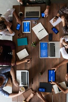 several people sitting at a table with laptops and notebooks on their lap tops