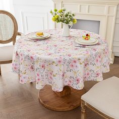 the table is set with two plates and flowers on it, along with some chairs