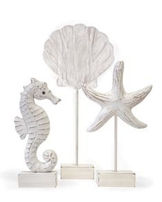 two seahorses are standing next to each other on white stands with seashells in the background