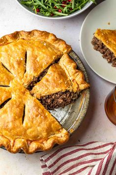 a pie sitting on top of a plate next to a salad