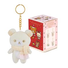 a white teddy bear keychain sitting next to a pink box with an animal on it