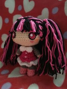 a small doll with pink hair is sitting on a red and white blanket, next to the caption that says dracula de monster high