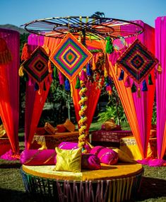 an elaborately decorated outdoor area with pink and orange drapes, pillows, and decorations