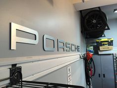 a garage with the word porsche written on the wall and gas pumps hanging from the ceiling