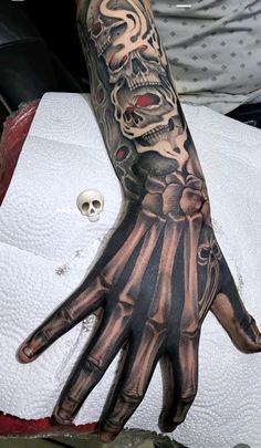 a person with a tattoo on their arm and hand is holding a skull in the air