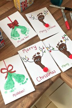 four christmas cards with handprints on them sitting on top of a wooden table