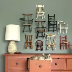 a cat laying on top of a dresser next to chairs