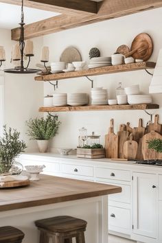 a kitchen filled with lots of white dishes and wooden shelves next to a counter top