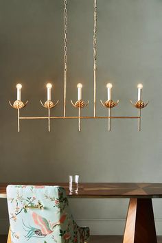 a chandelier hanging over a dining room table with a blue chair in front of it